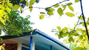 Uma casa de dois andares com varanda, varanda com cadeiras e gramado verde.