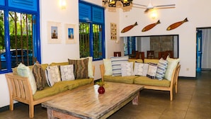Uma sala de estar com sofá de madeira, mesa de centro e ventilador de teto.