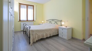 A bedroom with a bed, bedside tables, a window, and a radiator. - Casa gli Ulivi: New cozy apartment, a few kilometers from Montepulciano.  (Montepulciano)