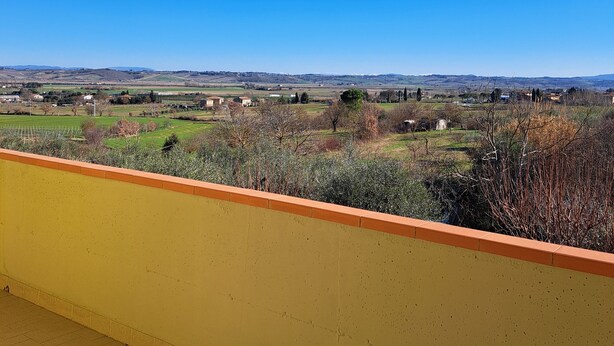 A balcony with a yellow wall and a view of a rural landscape with fields and distant hills. - Casa gli Ulivi: New cozy apartment, a few kilometers from Montepulciano.  (Montepulciano)