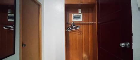 Une pièce avec une armoire en bois, un miroir et une porte rouge.