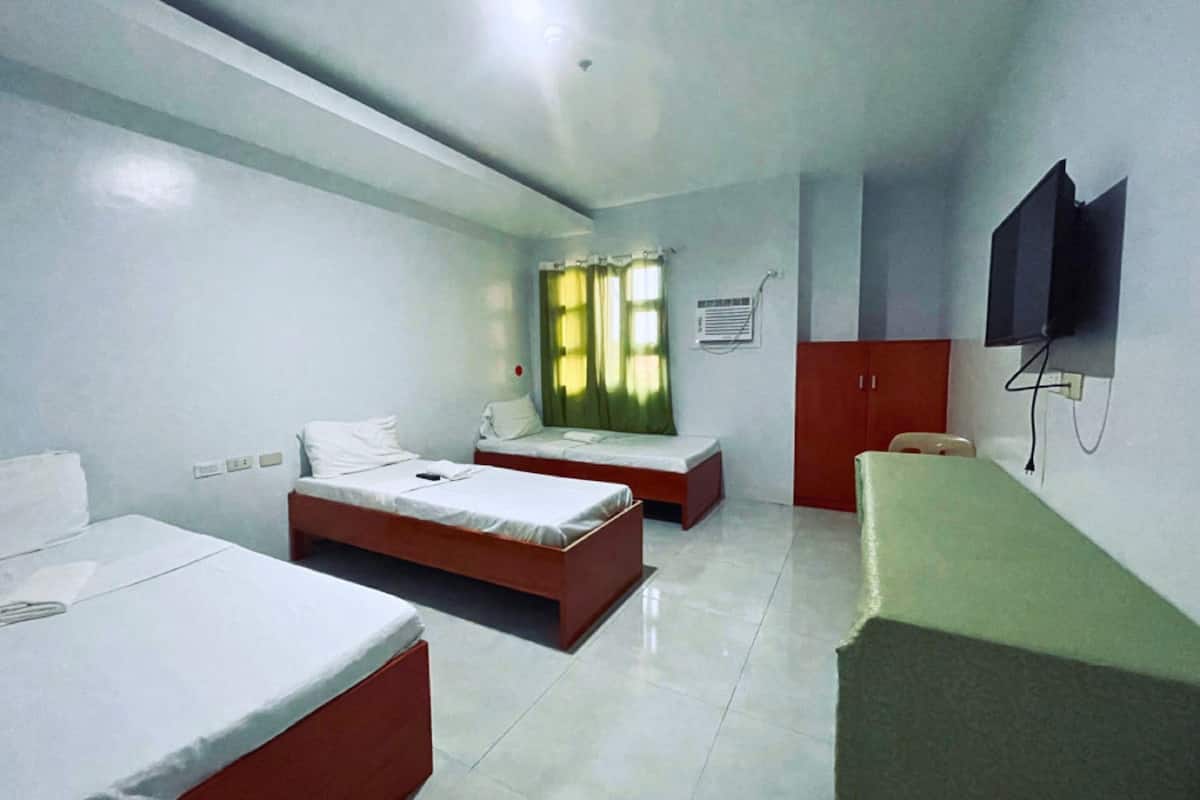 A hotel room with two single beds, a desk, a chair, a television, and a window with curtains.