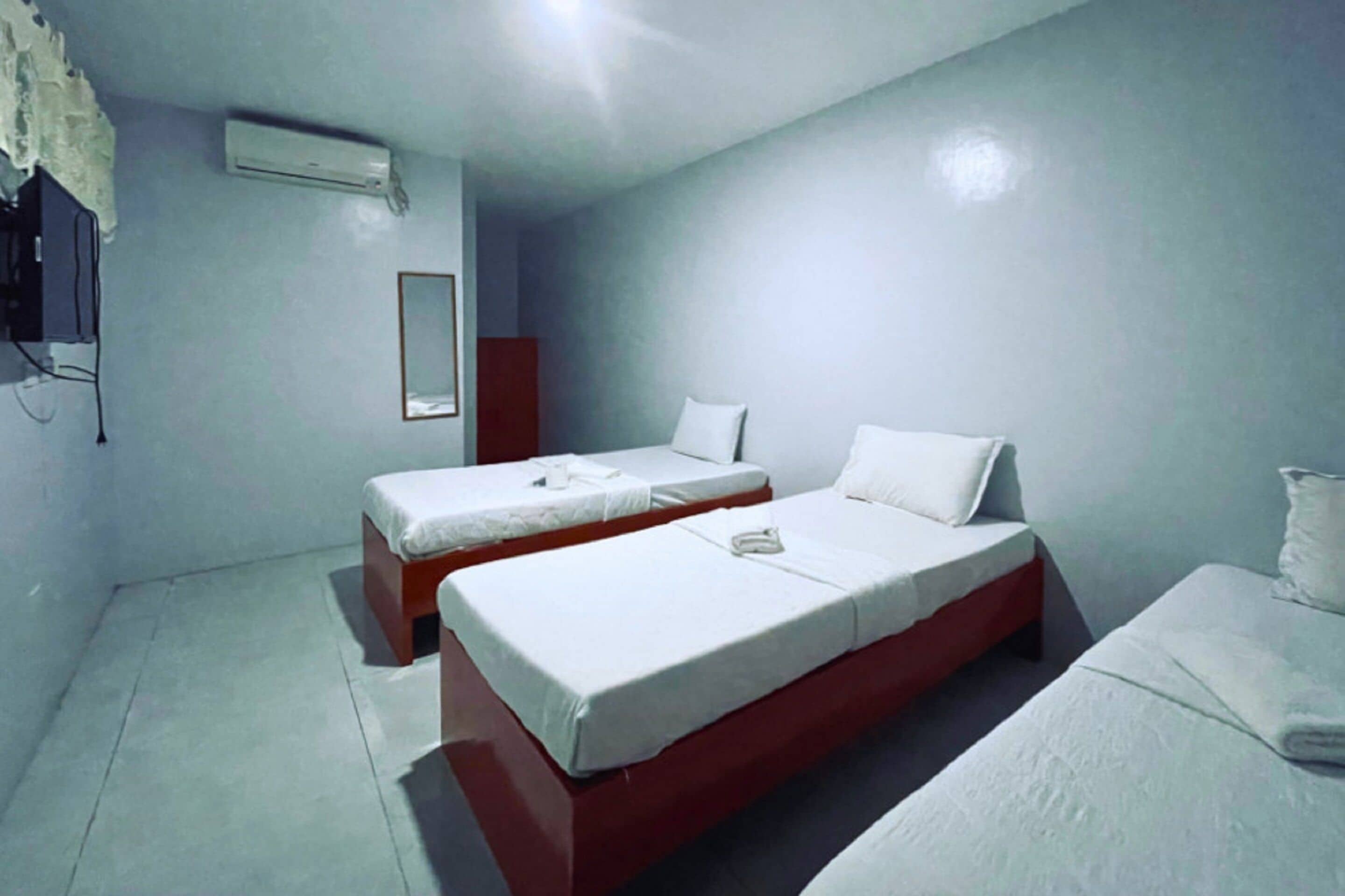 Una habitación con dos camas individuales, un espejo y un equipo de aire acondicionado.