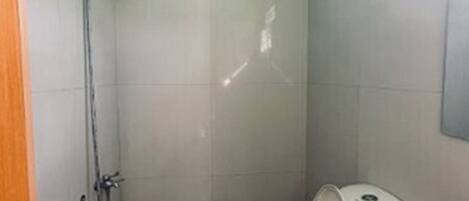 Une petite salle de bain avec une douche, des toilettes et un lavabo.