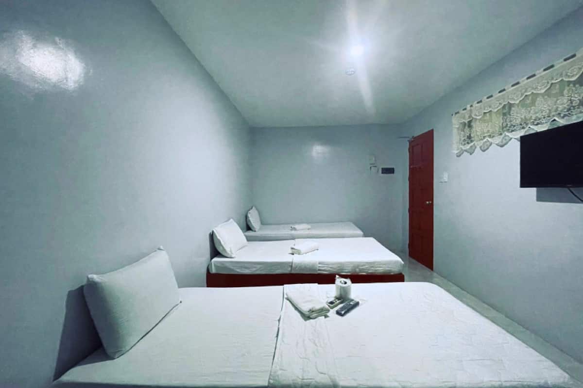 A small, clean room with three single beds, a TV mounted on the wall, and a simple, functional design.