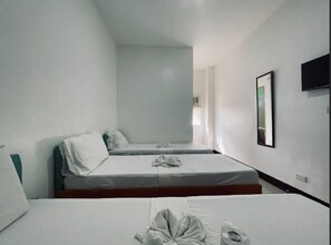 A small, sparsely furnished room with two single beds, a flat-screen TV mounted on the wall, and a window providing natural light. - A and A Bed & Breakfast Inn powered by Cocotel (Legazpi)