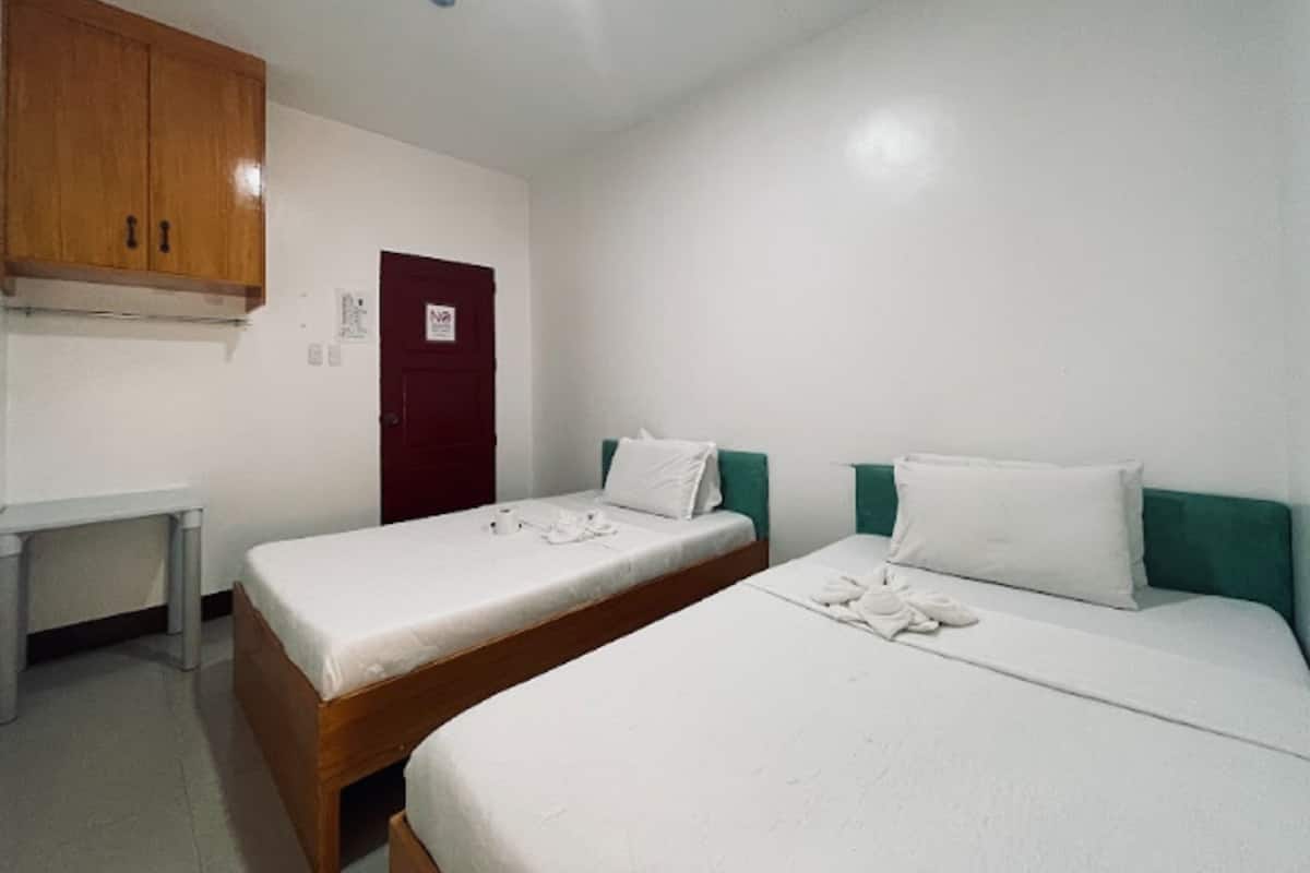 A room with two single beds, a wooden wardrobe, a desk, and a door with a 'No Entry' sign.