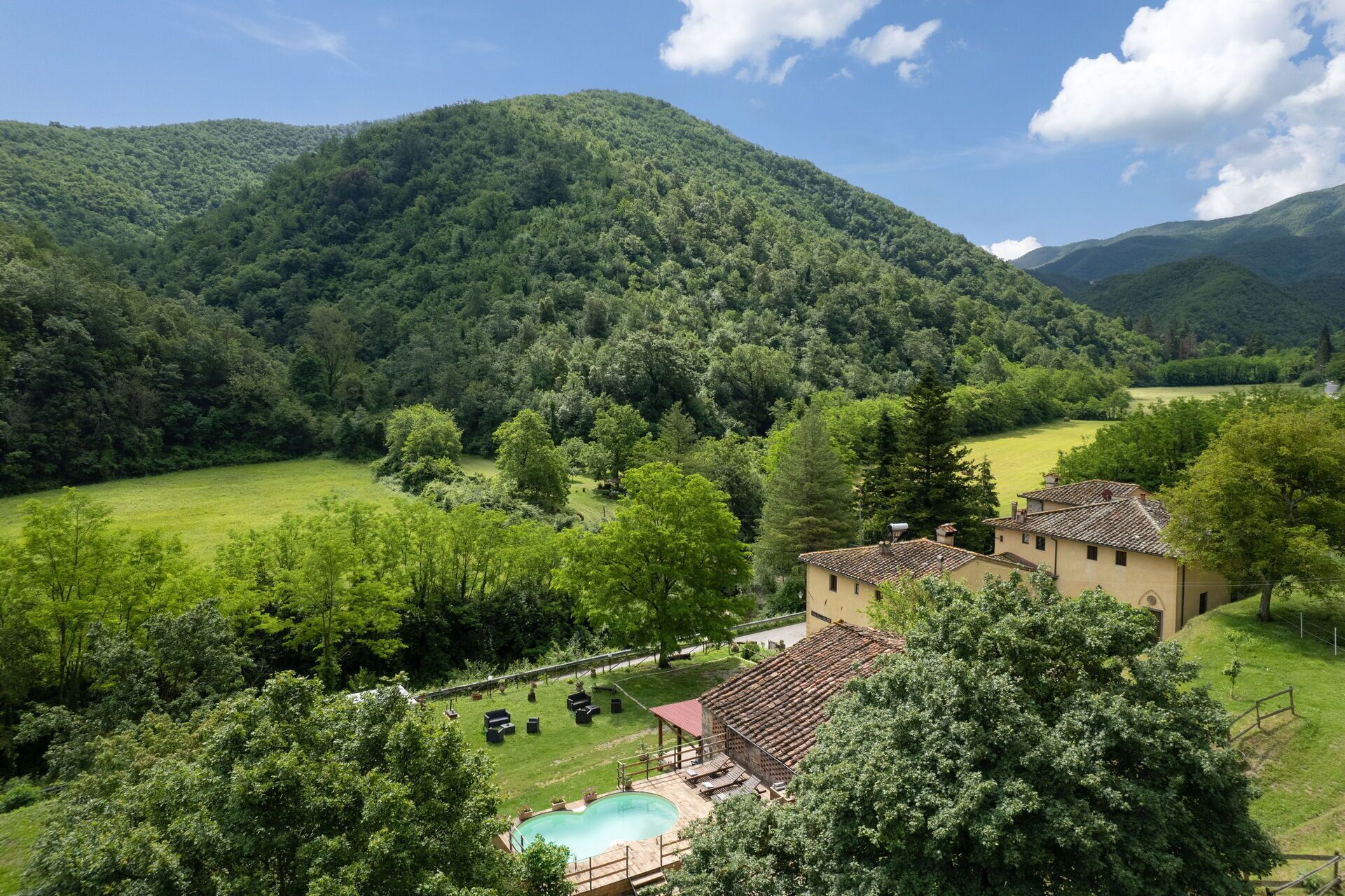 Une villa avec piscine, entourée d’une végétation luxuriante et de montagnes.