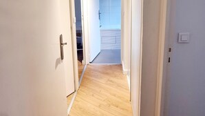 Ein Korridor mit Holzboden, weißen Wänden und einer Deckenleuchte.
