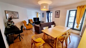 Ein modernes Wohnzimmer mit einem Holzespeisetisch, gelben Stühlen, einem Sofa und einem Fernseher.
