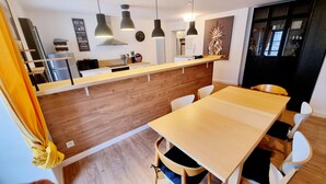 Eine moderne Küche mit Holzarbeitsplatten, Pendelleuchten und einem Essbereich mit einem Holztisch und Stühlen.