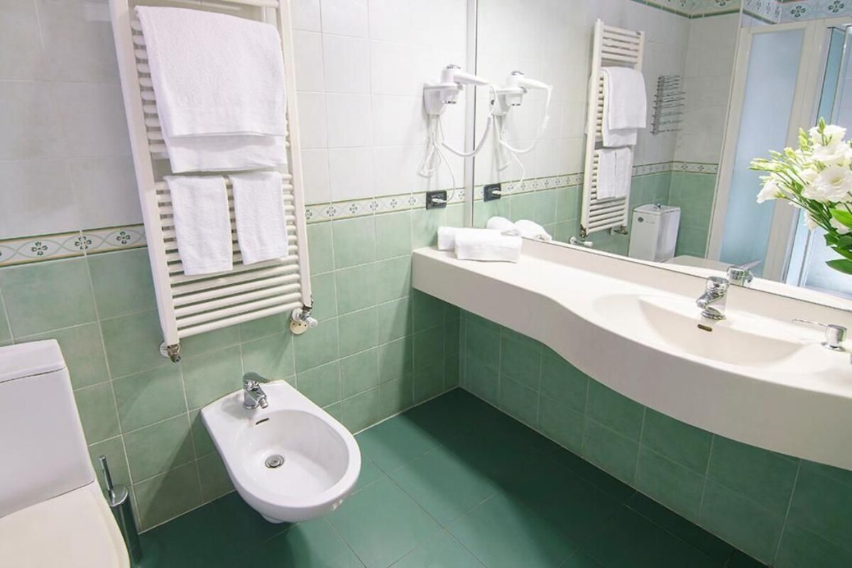 A bathroom with a toilet, bidet, and sink.