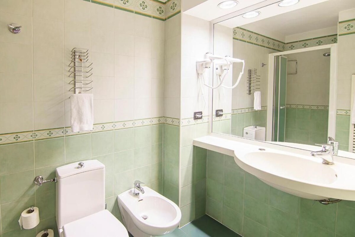 A bathroom with a toilet, bidet, and sink.