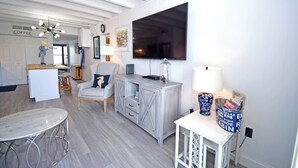 A modern living room with a TV, a coffee station, and a dining area. - Jada 2B-Oceanside 77th St, Free WiFi, Pool, Elev, W/D, AC (Ocean City)
