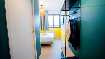 A hotel room with a bed, a wardrobe, and a suitcase.