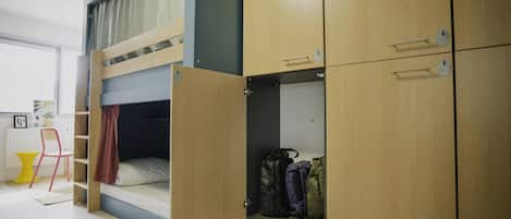 A bunk bed room with a wardrobe and a chair.