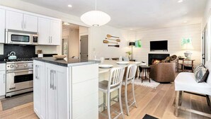 Une cuisine moderne avec des meubles blancs, un îlot central et un coin repas avec des chaises blanches.