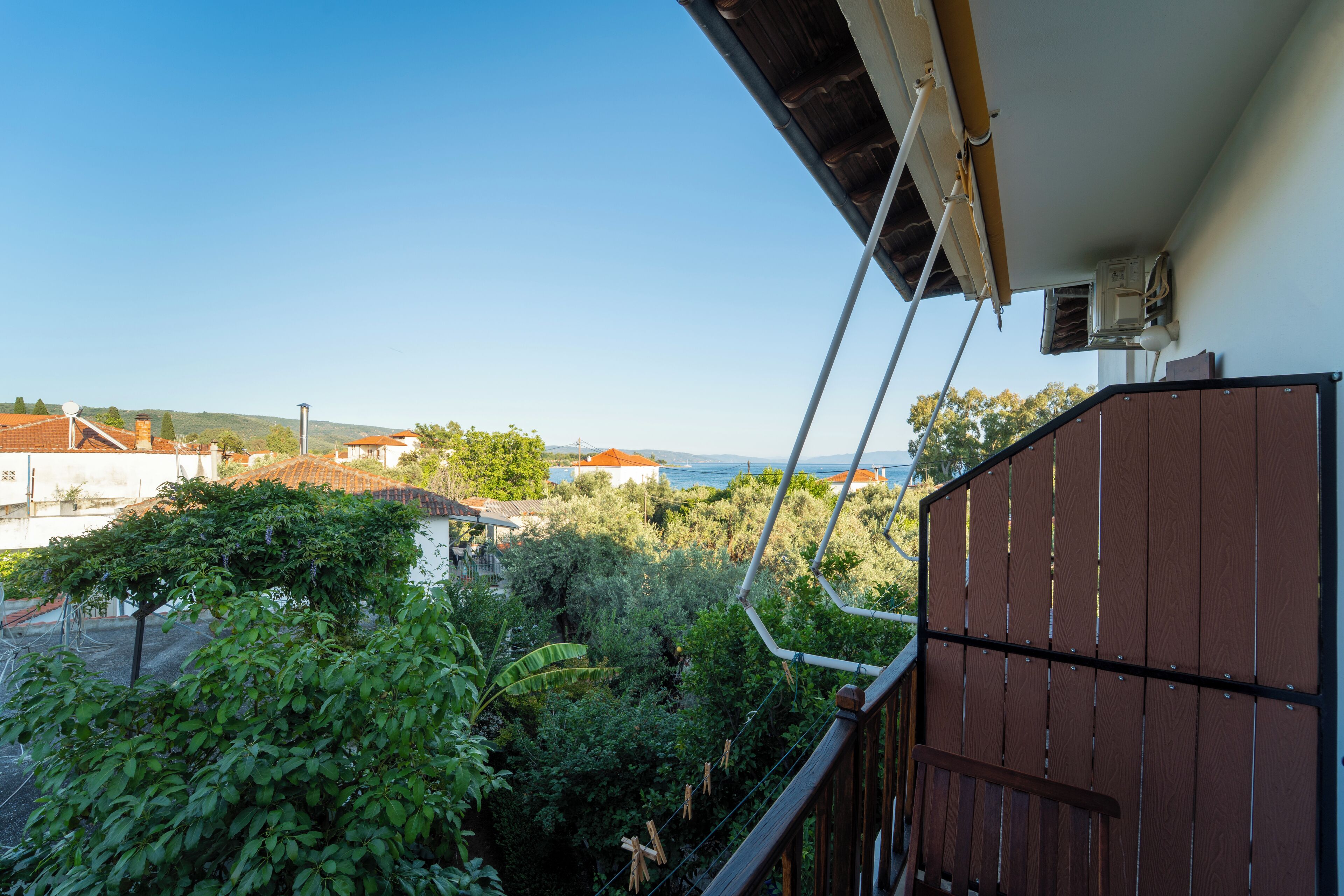 Un balcón con vistas a un jardín exuberante y edificios lejanos.