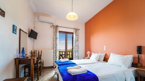Een hotelkamer met twee bedden, een bureau, een stoel, een televisie en een raam met gordijnen.