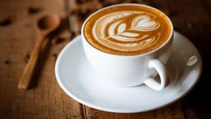 A cup of coffee with latte art on a saucer. - Roomshala 095 Shyam Villa (New Delhi)