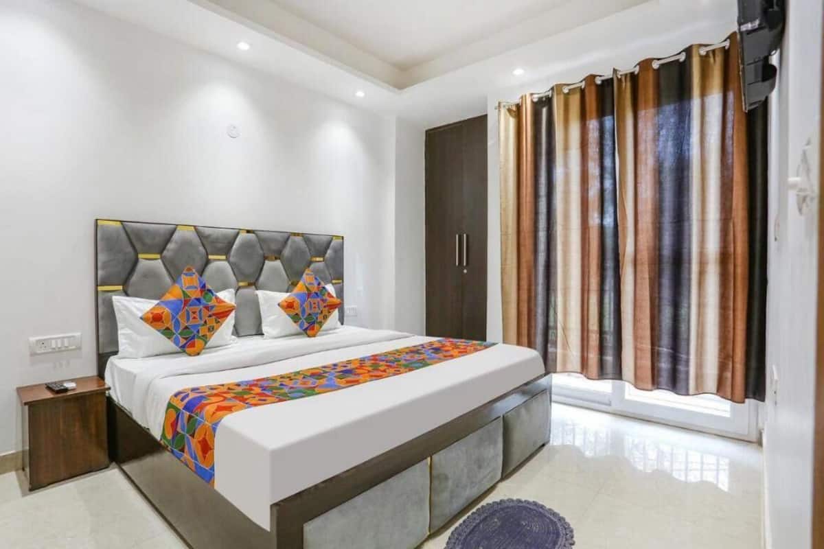 A modern bedroom with a large bed, a headboard with geometric patterns, a wardrobe, and a window with curtains.