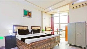 A bedroom with a large bed, a nightstand, a wardrobe, and a window with curtains. - Roomshala 095 Shyam Villa (New Delhi)