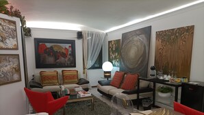 A modern living room with a sofa, armchairs, a coffee table, and artwork on the walls. - Contemporary Art apartments by Spanish steps, Cozy space in the center of Rome. (Roma)