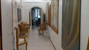 A hallway with a tiled floor, wooden chairs, a bench, and a large abstract painting on the wall. - Contemporary Art apartments by Spanish steps, Cozy space in the center of Rome. (Roma)