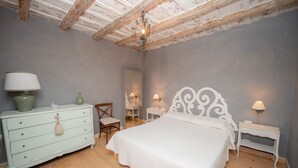 A bedroom with a wooden ceiling, a white bed, a dresser, a chair, and two bedside tables with lamps. - Big Family Villa in Rome Countryside (Rocca di Papa)