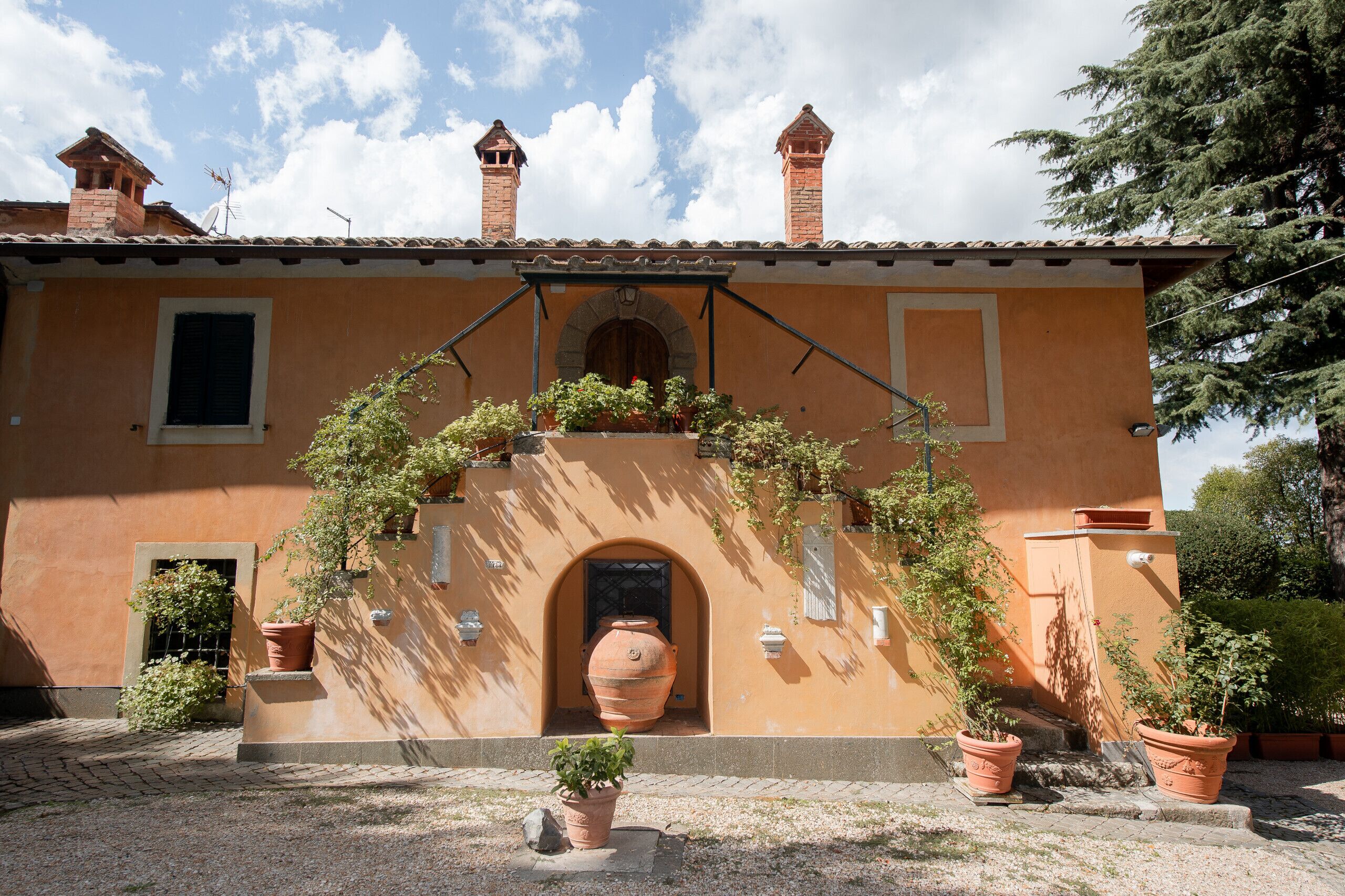 A building with a tiled roof, a central archway, and potted plants.