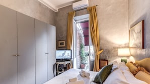 A hotel room with a bed, a television, a wardrobe, and a window with curtains.