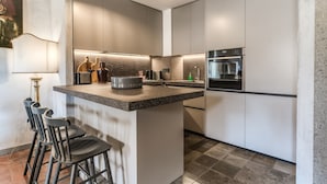 A modern kitchen with a central island, bar stools, and built-in appliances.