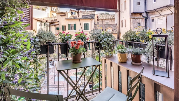 A balcony with potted plants, a table, and chairs.