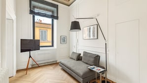 A room with a grey sofa, a standing floor lamp, a television on a tripod, and a radiator. - Charm and Style by The Spanish Steps (Roma)