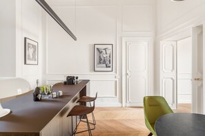 A modern kitchen with a bar area, white cabinetry, and a dining area with a green chair. - Charm and Style by The Spanish Steps (Roma)
