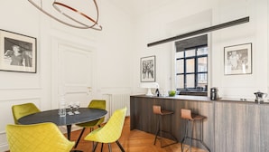 A modern kitchen with a central island, bar stools, and a dining area with yellow chairs. - Charm and Style by The Spanish Steps (Roma)