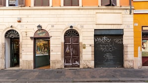 A building facade with numbered doors, a closed shutter, and a street in front.