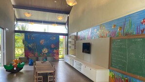 Une salle de classe ornée d’une fresque représentant des scènes sous-marines, avec un tableau noir et une table entourée de chaises.