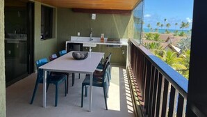 Un balcon doté d’un espace repas, d’un évier et offrant une vue sur l’océan et les palmiers.