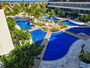 Un resort con varias piscinas, palmeras y zonas de descanso.