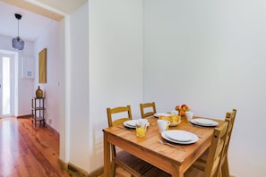 A dining area with a wooden table set for breakfast, including plates, cups, and a fruit bowl. - Casa de Santana (Lisbon)