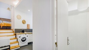 A modern hotel room with a bed, a washing machine, and a small kitchenette. - Casa de Santana (Lisbon)