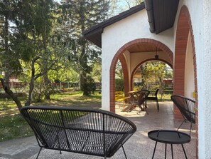 Eine Terrasse im Freien mit Ziegelbögen, schwarzen Metallstühlen und einem kleinen Tisch.