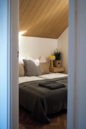 Relax in this inviting bedroom with a sloped ceiling, a comfortable bed, and a cozy reading nook.