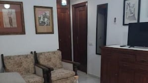 A living room with a sofa, two armchairs, a coffee table, a TV on a cabinet, and framed pictures on the wall. - Apartamento Barrio Santa Cruz, Centro Sevilla (Sevilla)