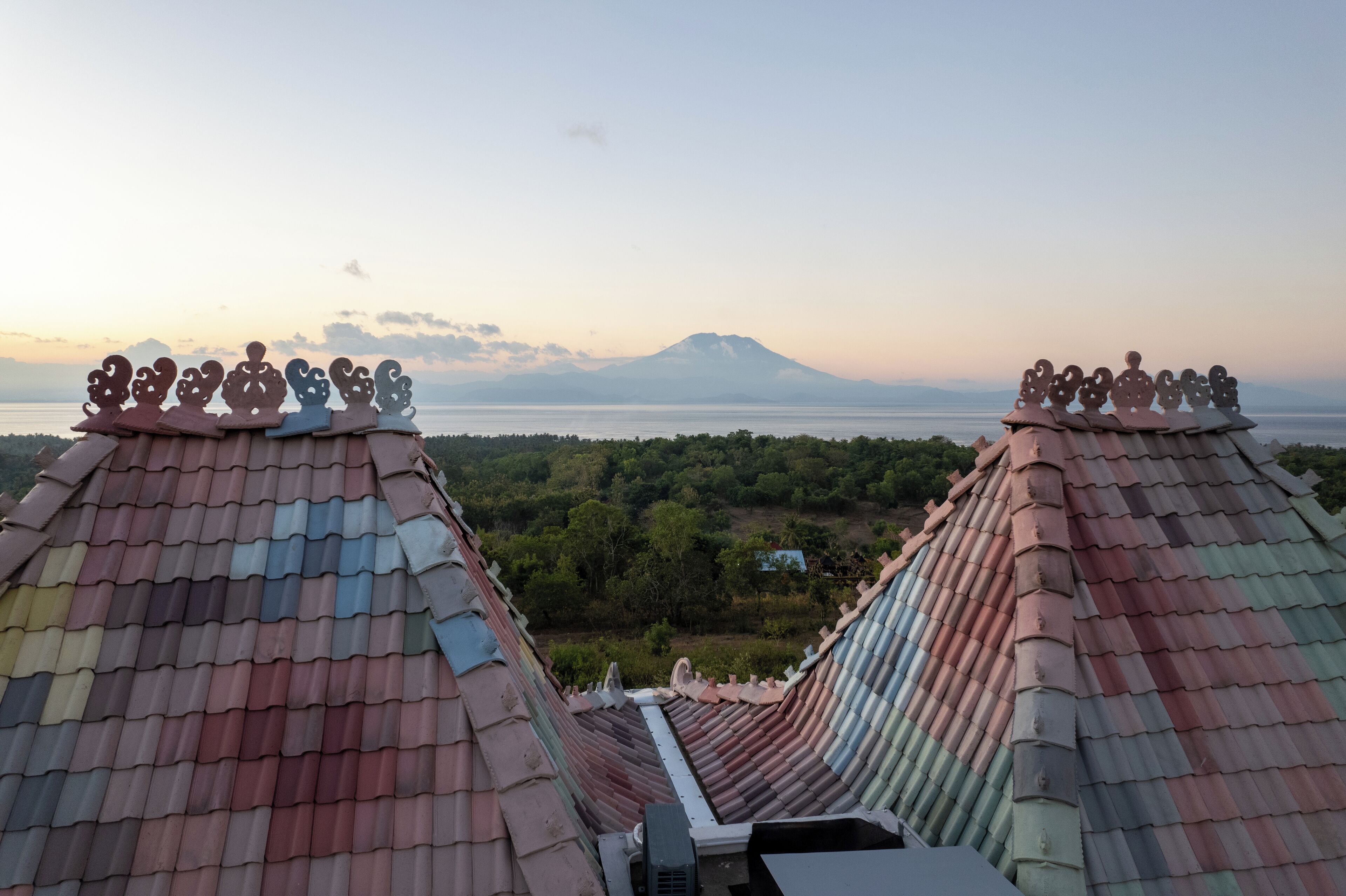 A traditional roof with decorative elements and a view of a mountain and water body.