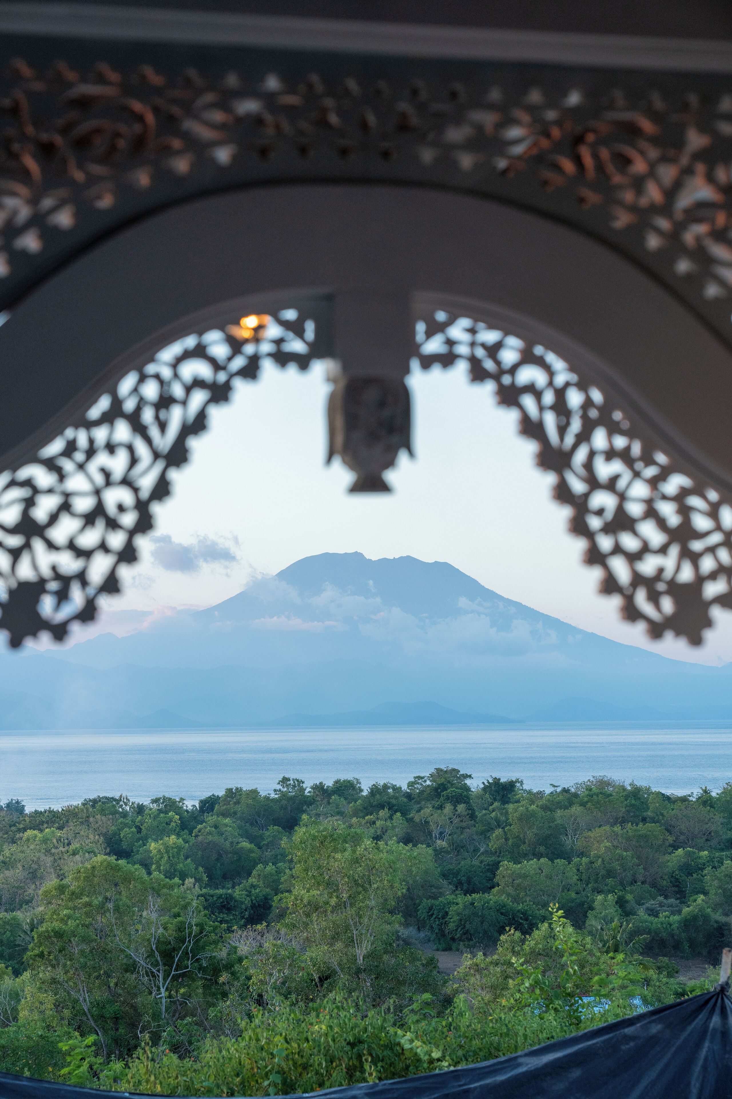 A view through an ornate window with a mountain in the background.