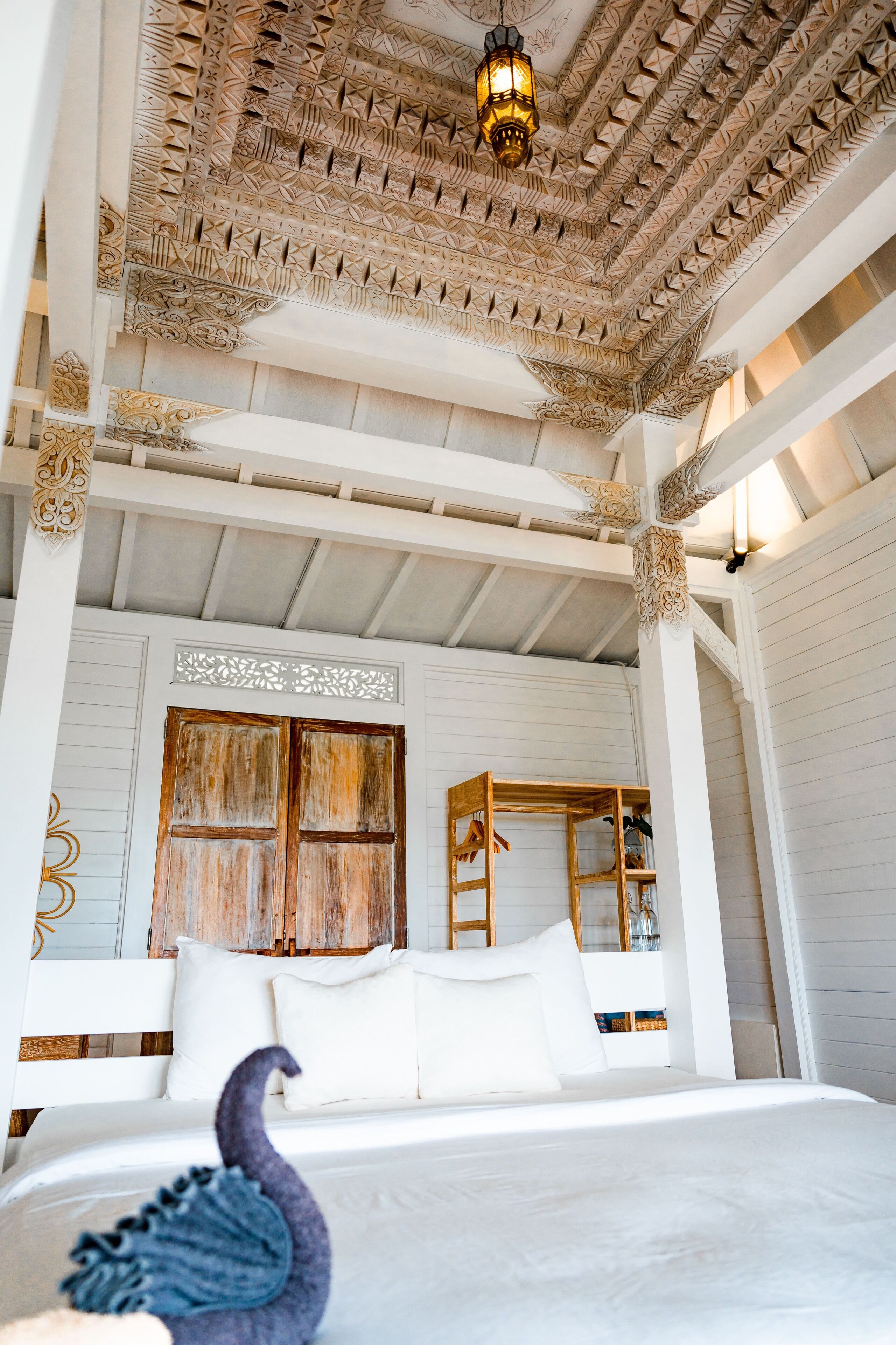 A bed with white linens, a wooden headboard, and a decorative ceiling with intricate patterns.