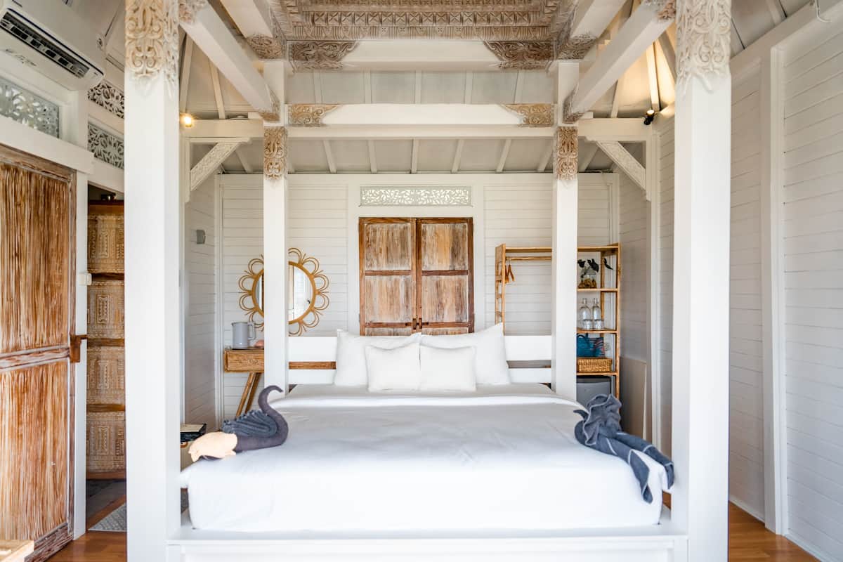 Quarto com cama de dossel, guarda-roupa de madeira e espelhos decorativos.