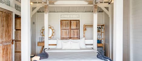 Quarto com cama de dossel, guarda-roupa de madeira e espelhos decorativos.